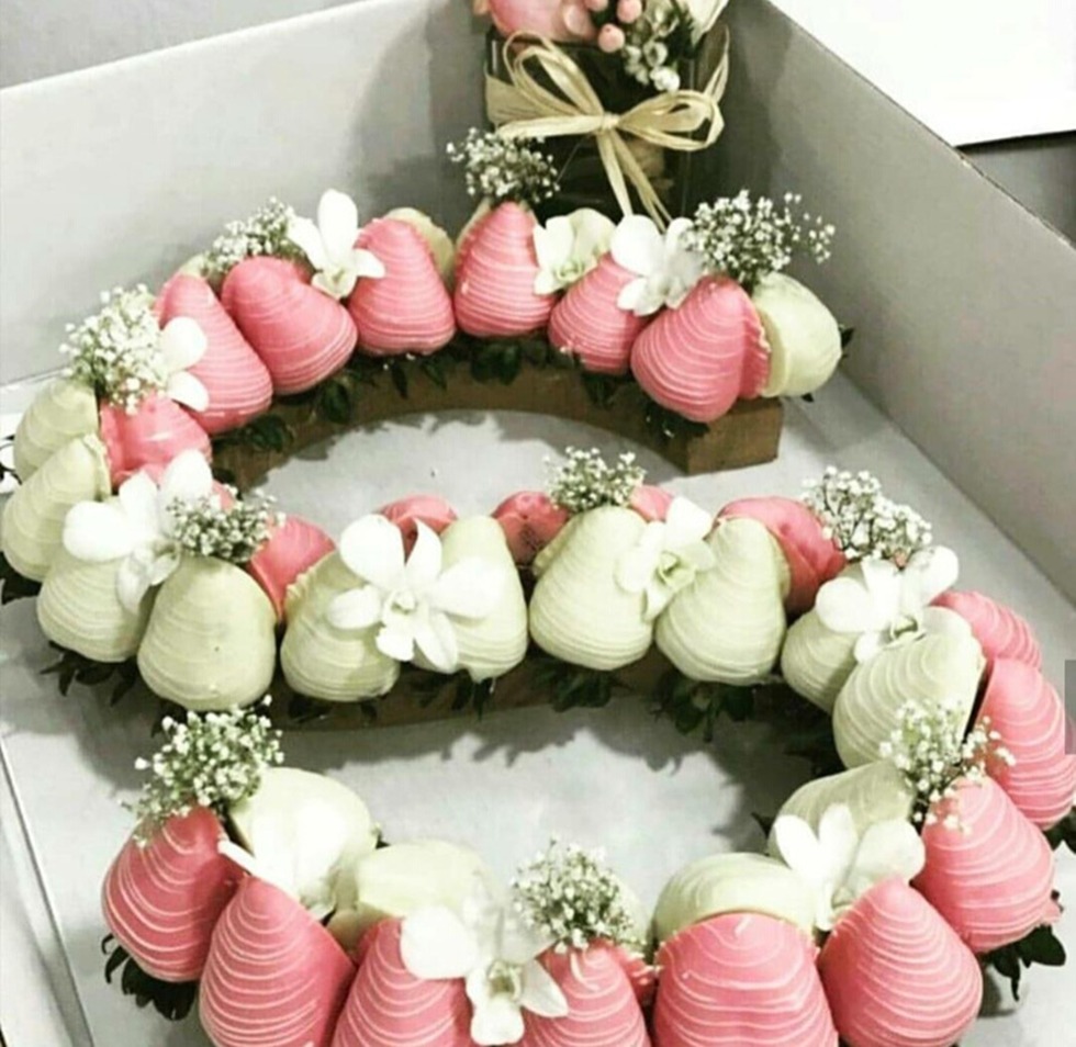 Fresas cubiertas de chocolate y flores formando la letra de tu preferencia